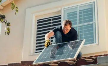 Monteur van zonnepanelen op een dak die een zonnepaneel installeert