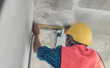 Een bouwvakker die het dak opmeet om uiteindelijk de prijs van dakisolatie te bepalen